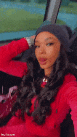 a woman is taking a selfie in a car while wearing a beanie .