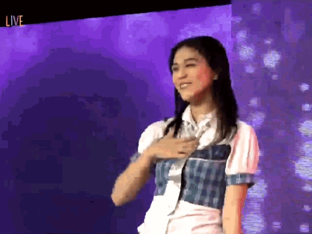 a woman is standing in front of a purple background with the word live on it