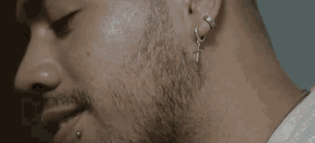 a close up of a man 's face with a beard and earrings