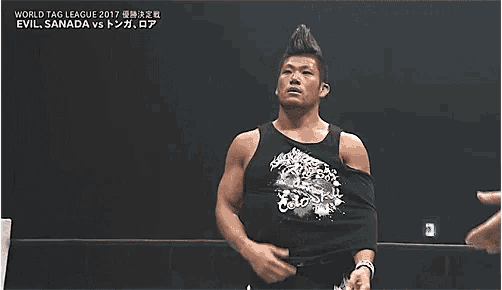 a man without a shirt is standing in a wrestling ring with his hands behind his head .