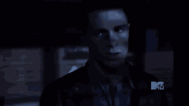 a close up of a person 's face in a dark room with a mtv logo in the background .