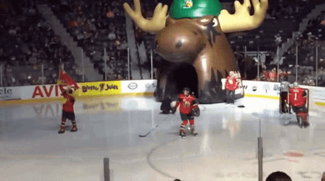a hockey game is being played in front of a moose shaped tunnel that is sponsored by avis