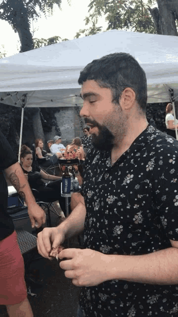 a man in a floral shirt is eating a piece of food