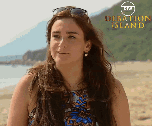 a woman wearing sunglasses stands on a beach in front of a sign that says " debatic island "