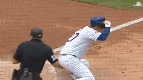 a baseball player is getting ready to hit the ball while a referee looks on .