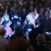 a crowd of people are gathered in a dark room and one of them is wearing a shirt that says r.i.p