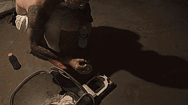 a shirtless man is squatting on the floor while holding a bottle .