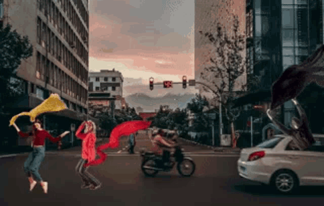 a man on a motorcycle is driving down a city street with people dancing in the background