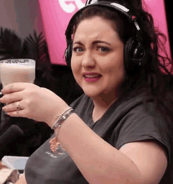 a woman wearing headphones is holding a cup of milk