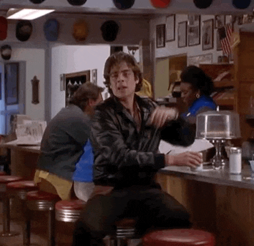 a man is sitting at a counter in a diner holding a cup of coffee .
