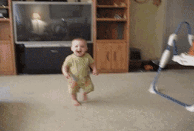 a baby is running in a living room in front of a tv