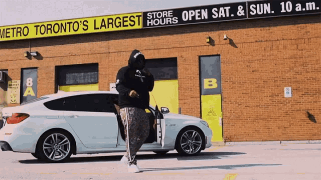 a white car is parked in front of a building that says metro toronto 's largest hours