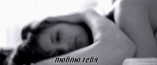 a black and white photo of a woman laying in bed with her head on her arms .
