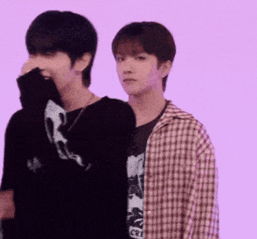 a couple of young men are standing next to each other on a purple background .