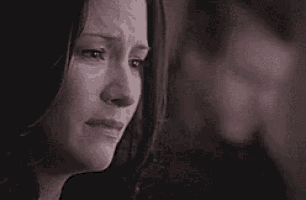 a close up of a woman crying with a man behind her .