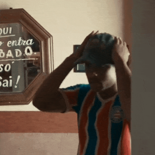 a man adjusts his hat in front of a sign that says qui entra badq