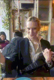 a woman is sitting at a table with a camera strap around her waist