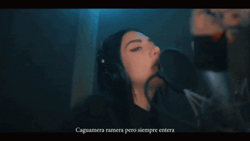 a woman singing into a microphone with the words caguamera ramira pero siempre entera written below her