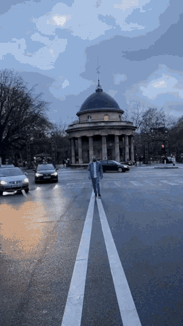 a man walking across a street in front of a building with a dome