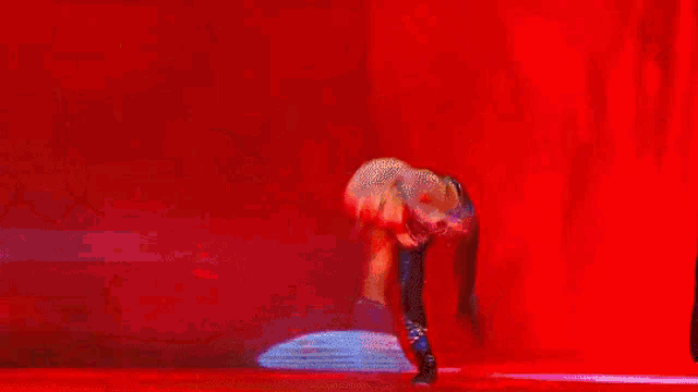 a woman in a wrestling outfit is flexing her muscles on a stage .
