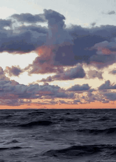 a cloudy sky over a body of water with waves
