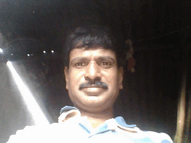 a man with a mustache looks at the camera and smiles