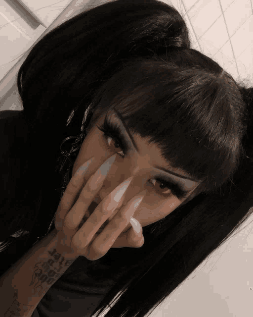 a woman with long nails and red eyes has a tattoo on her arm that says ' i 'm a ghost '