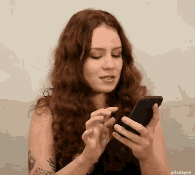 a woman with a tattoo on her arm is using a cell phone
