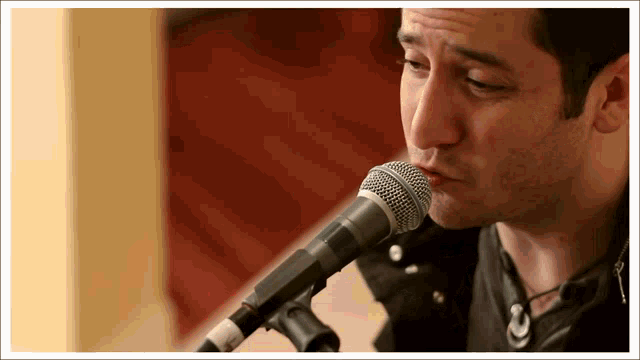 a man singing into a shure microphone while wearing a leather jacket