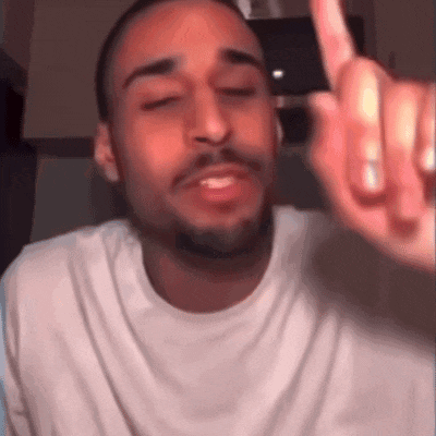 a man with a beard wearing a white t-shirt is giving the middle finger