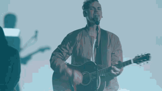 a man is singing into a microphone while playing a guitar