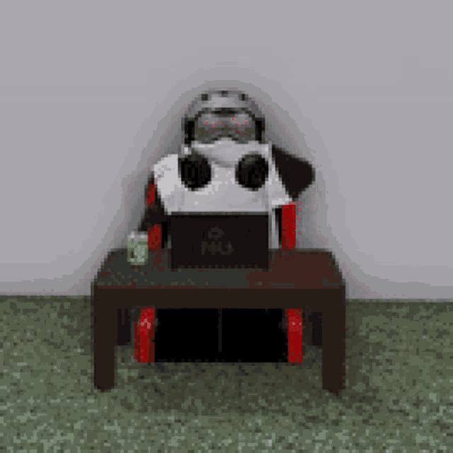 a robot is sitting at a table with a laptop and headphones .