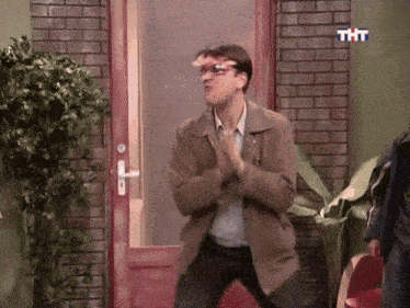 a man is dancing in front of a red door with tht written on it