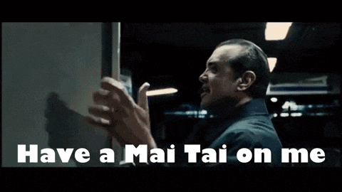 a man is standing in front of a vending machine and saying have a mai tai on me .