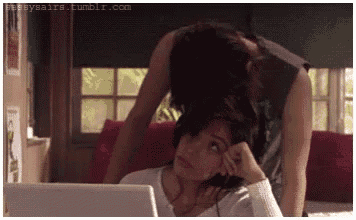 a man is putting his head on a woman 's head while they look at a laptop .