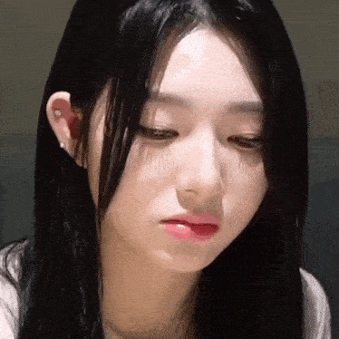 a close up of a woman 's face with long black hair and a red lip .