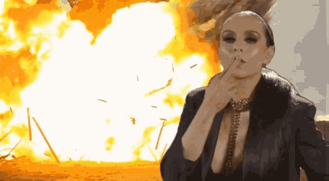a woman smoking a cigarette in front of a fire explosion