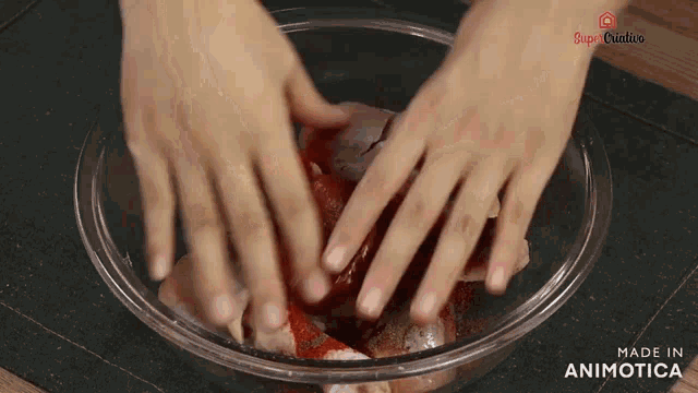 a person 's hands are in a glass bowl that says made in animonica