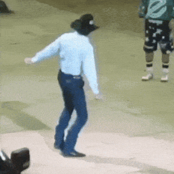 a man in a cowboy hat is dancing in front of a man in a green shirt .