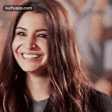 a close up of a woman 's face with a nose ring smiling .
