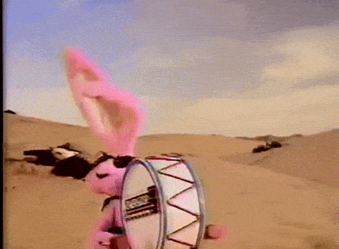 a pink bunny rabbit is holding a drum in the desert