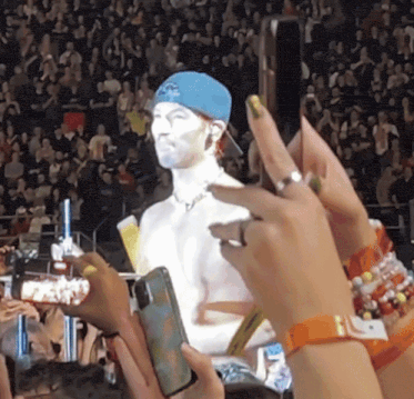 a shirtless man in a blue hat is being photographed by fans