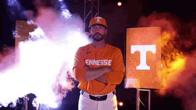 a man in an orange tennessee jersey stands with his arms crossed in front of an orange t