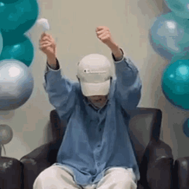 a man is sitting in a chair with his arms in the air and holding a balloon .