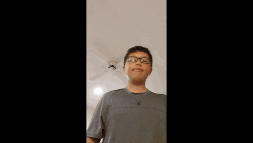 a boy wearing glasses giving the middle finger in front of a sign that says do not