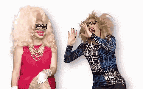 two drag queens are sitting next to each other and laughing .