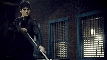 a man is holding a bow and arrow while standing in front of a brick building .