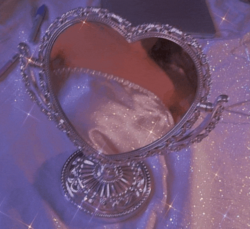 a heart shaped mirror on a purple cloth