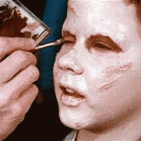 a person is applying makeup to a young boy 's face
