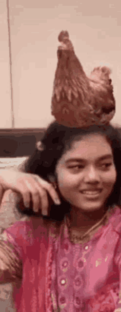a girl with a chicken on her head is smiling .